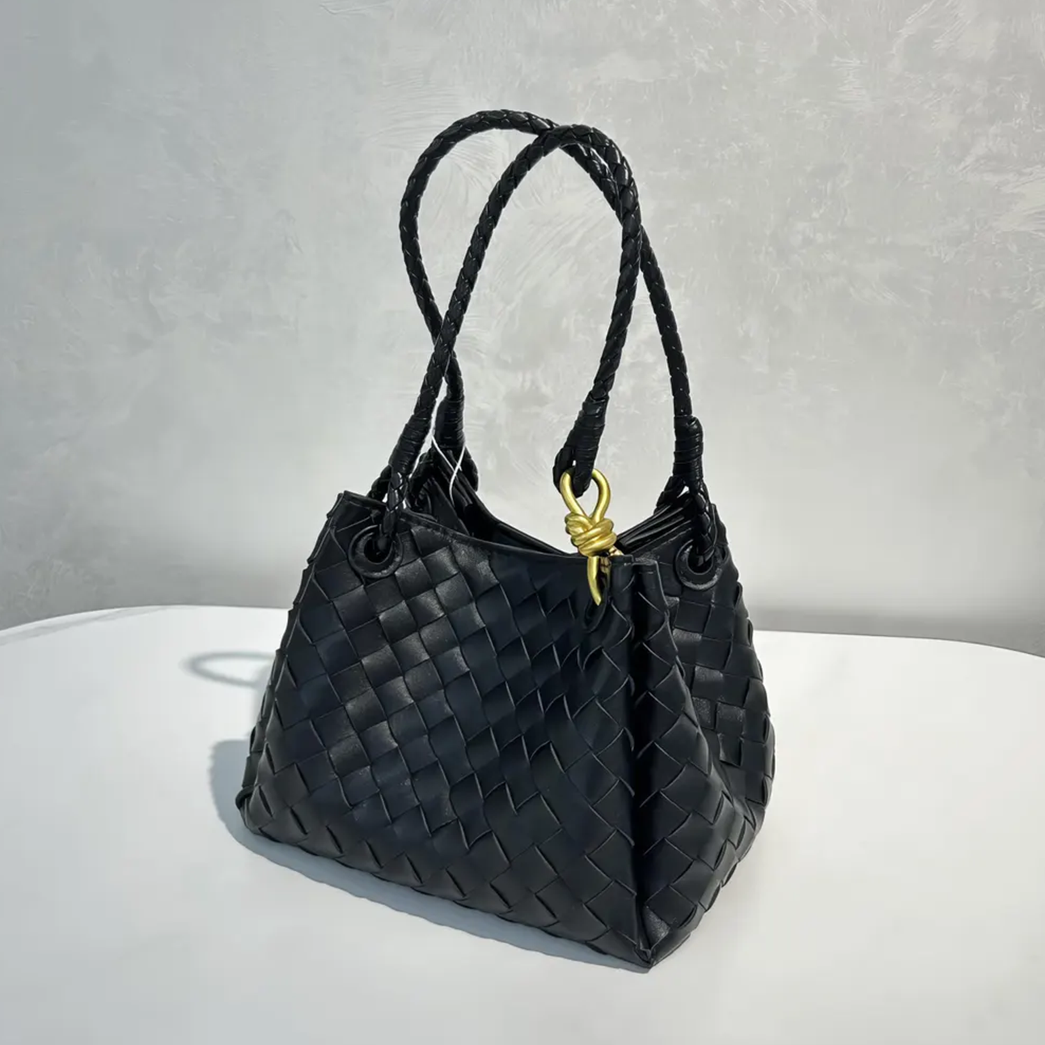 Dense Grid Woven Sloped Tote With Braided Twisted Top Handles, Knotted Golden Central Clasp And Extra Single Hanging Strap